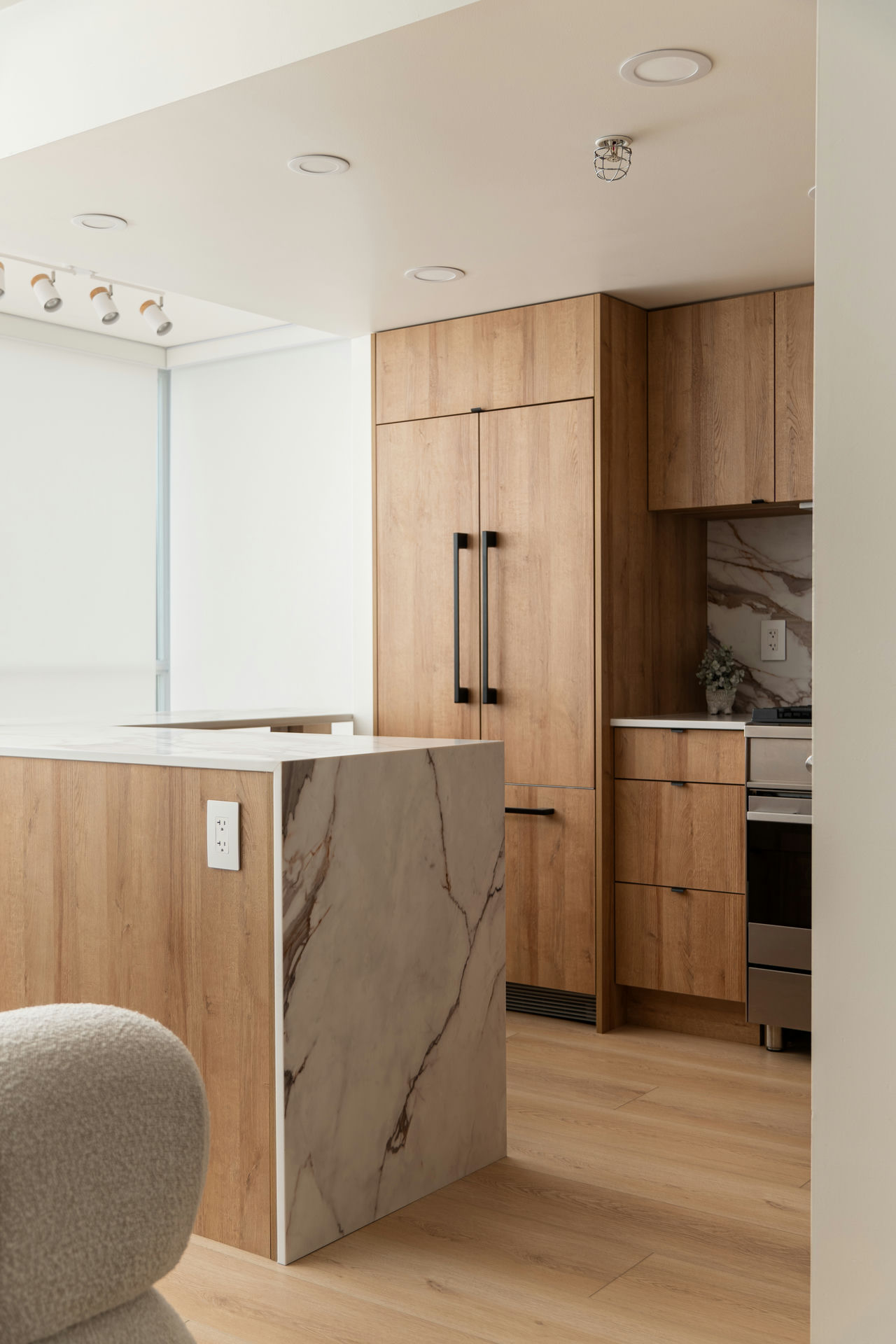 Modern kitchen renovation with sleek wood cabinetry, integrated appliances, and a marble waterfall island for a clean, contemporary look