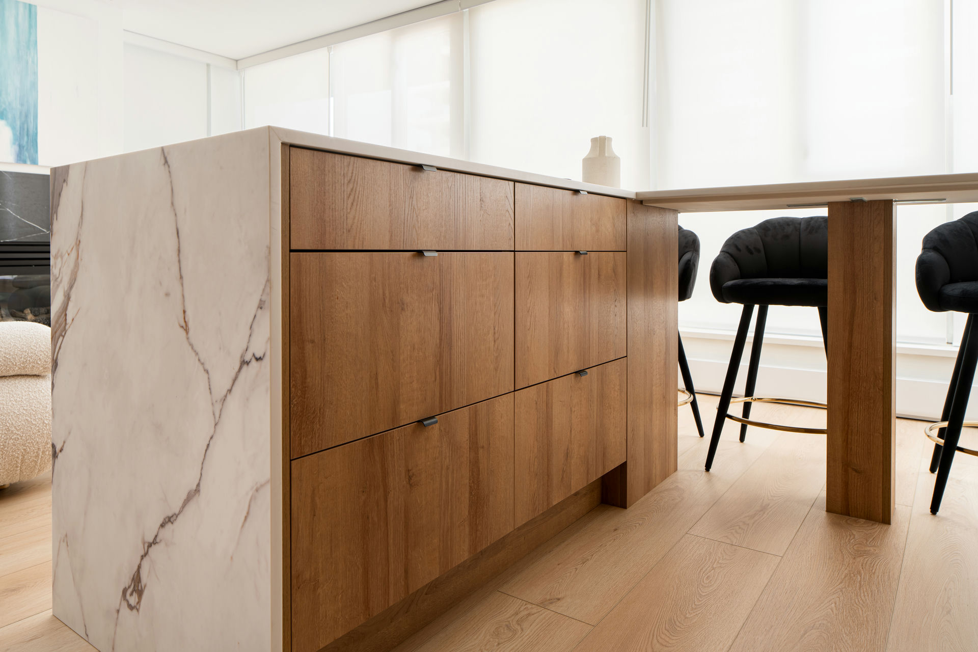 Streamlined kitchen renovation island with natural wood drawers and marble waterfall edges, blending storage with timeless design
