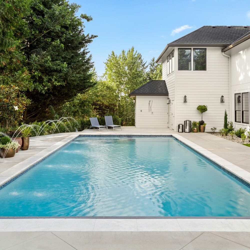 Luxury custom home featuring a spacious backyard, modern landscaping, and a private pool