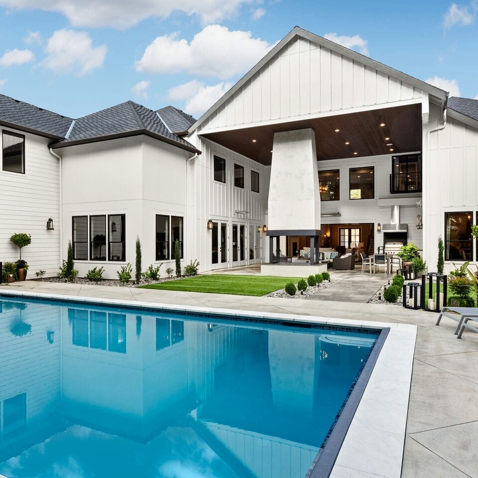 Contemporary custom home design with a backyard pool, patio lounge, and elegant exterior finishes