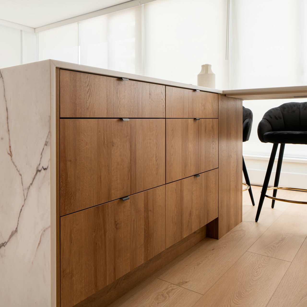 Streamlined kitchen renovation island with natural wood drawers and marble waterfall edges, blending storage with timeless design